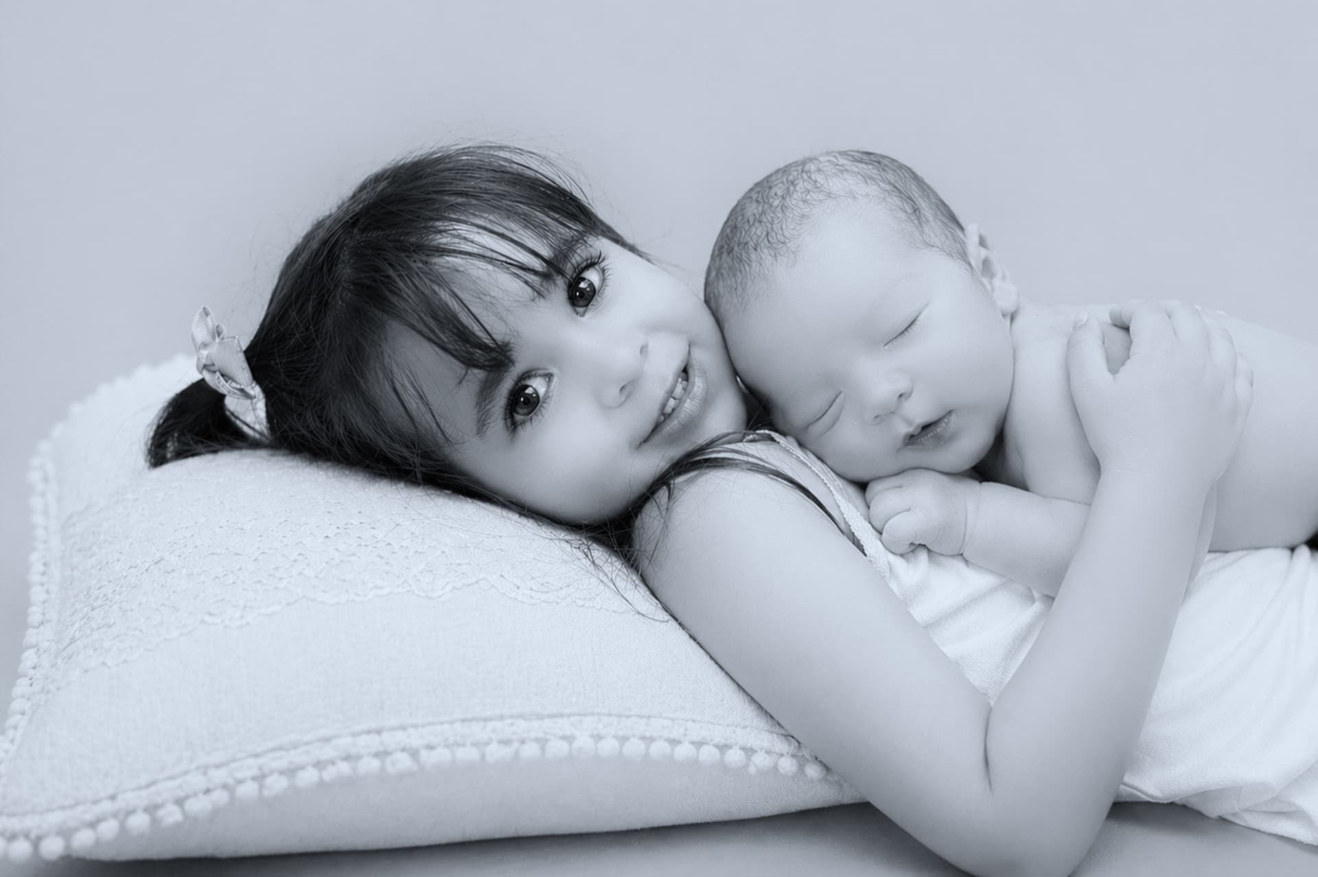 Hermana mayor abrazando a su hermano recién nacido en el estudio de Hellen Violet Fotografía