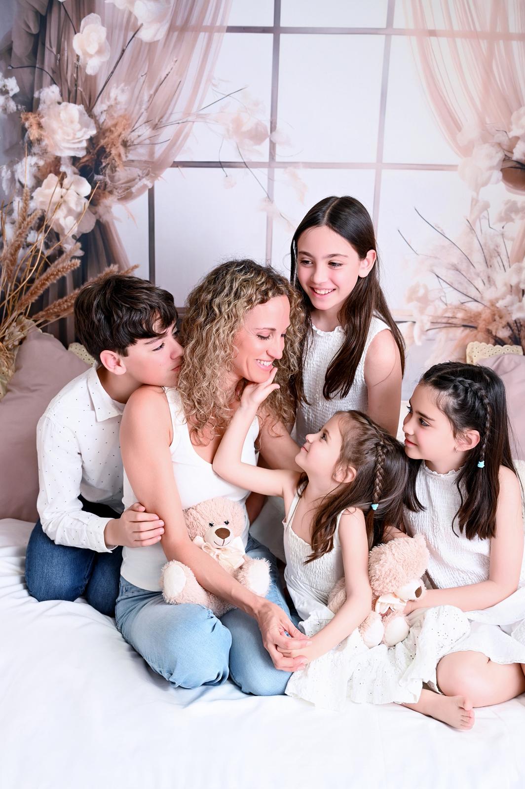 Familia tumbada en la cama del estudio durante una sesión de verano