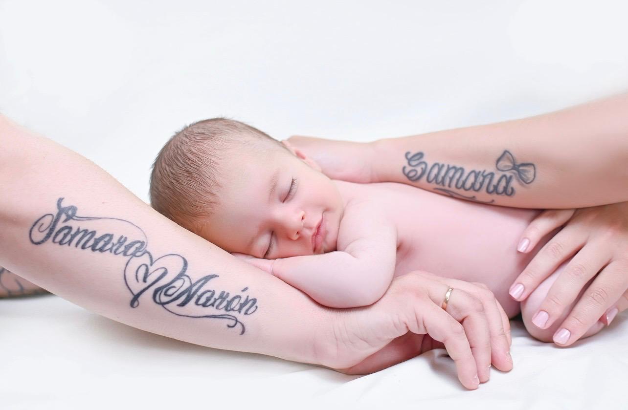 Bebé recién nacido dormido piel con piel entre los brazos de sus padres