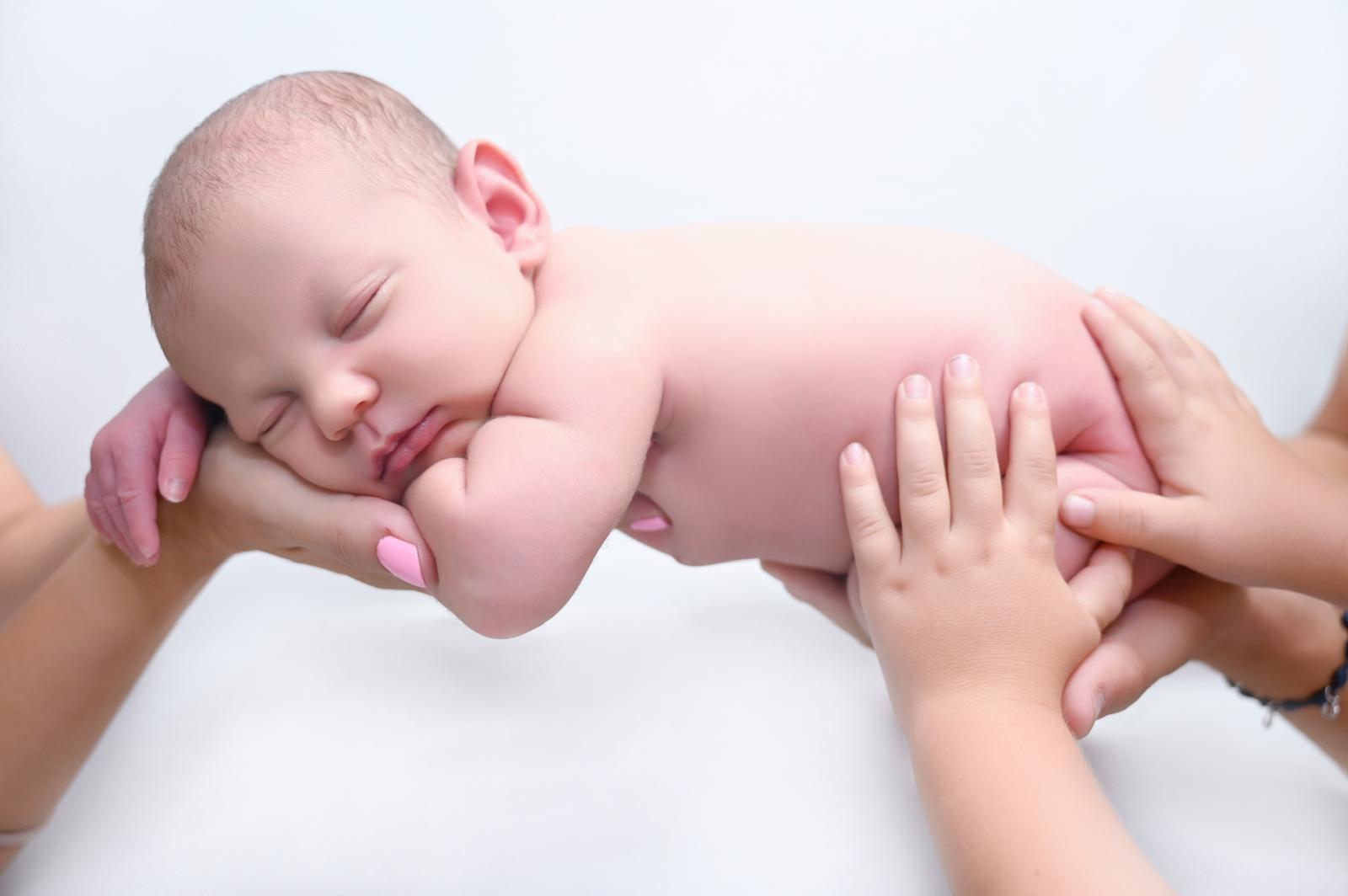 Recién nacido sostenido entre las manos de sus padres en el estudio newborn de Hellen Violet en Fuenlabrada
