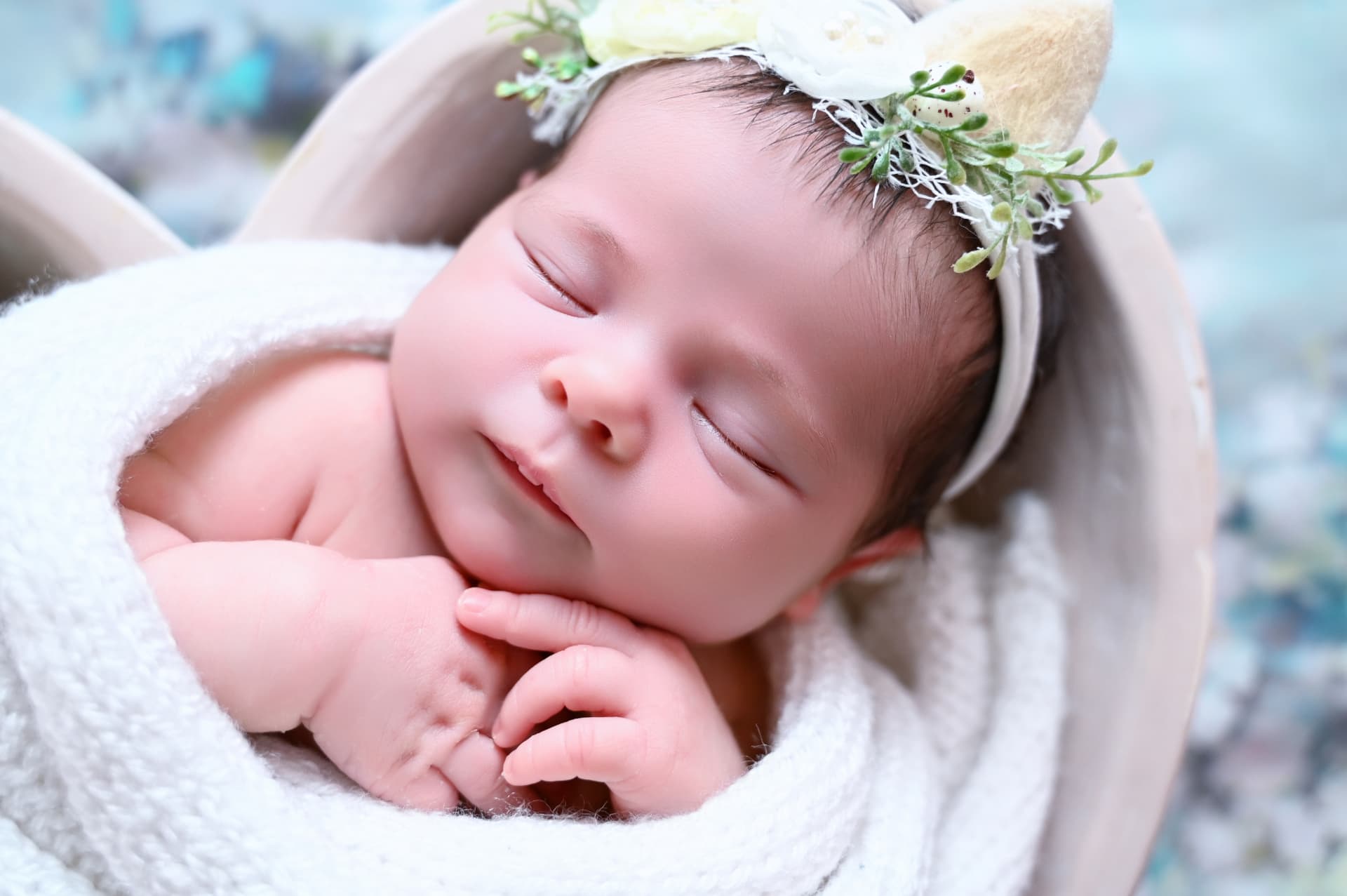 Bebé recién nacido dormido con corona de flores durante su sesión newborn en Fuenlabrada